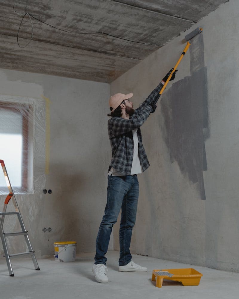 Peintre en bâtiment peignant un mur au rouleau